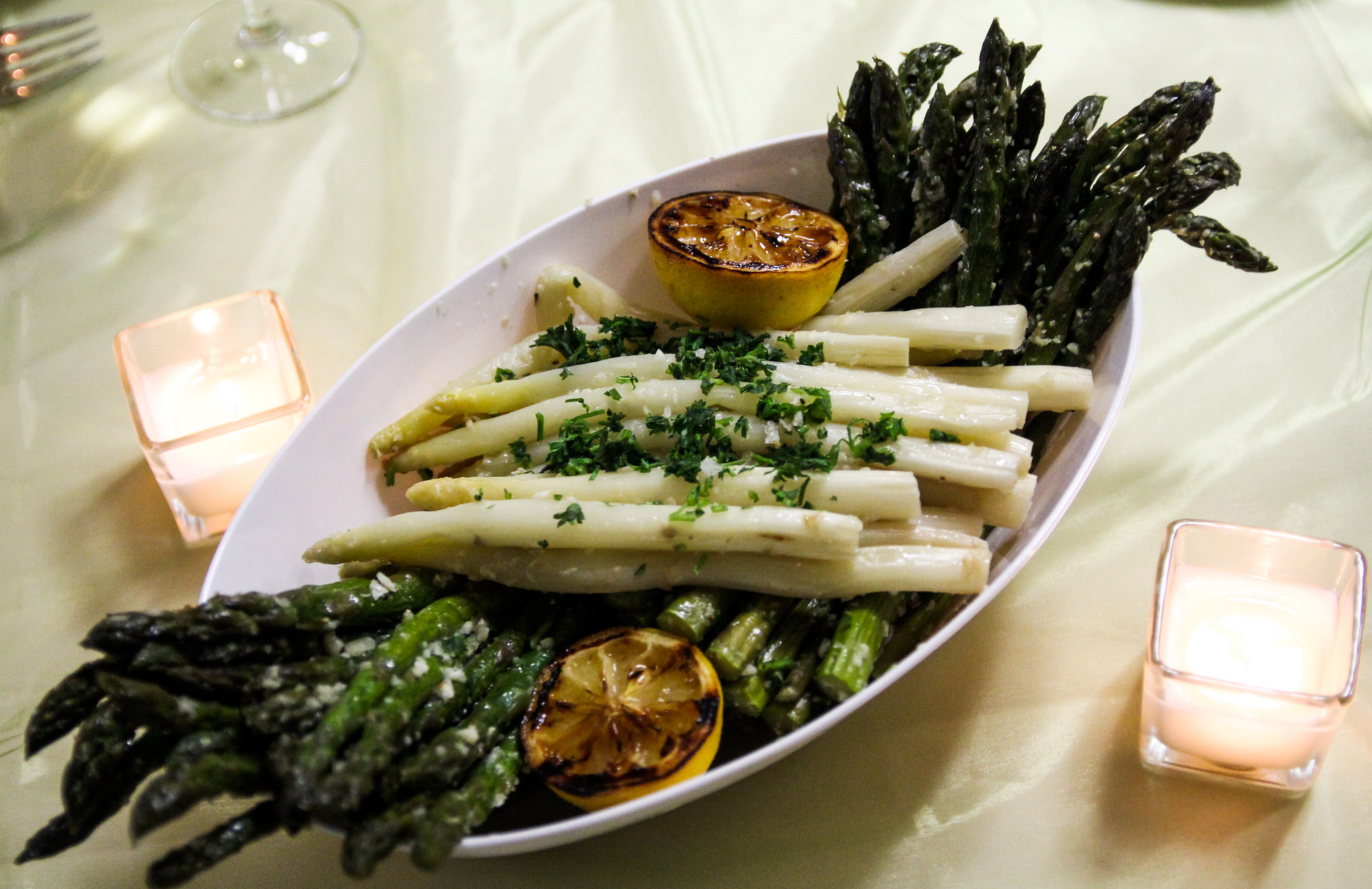 A dish of Asparagus with grilled lemon halves.