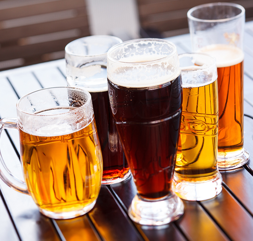 Different mugs and glasses filled with different types of beer on a table