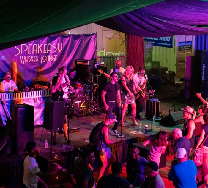 Band playing on the Speakeasy Whiskey Lounge stage with a crowd of dancing people
