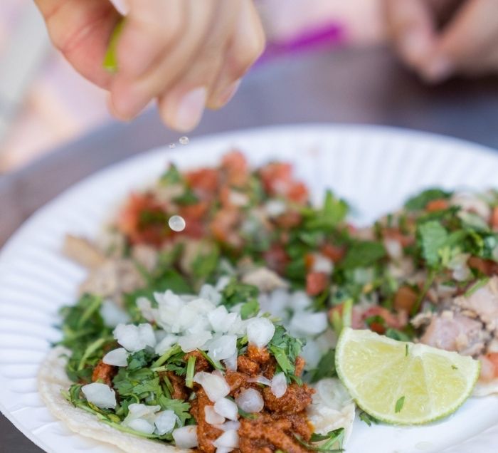 Hand squeezing lime on a plate of tacos